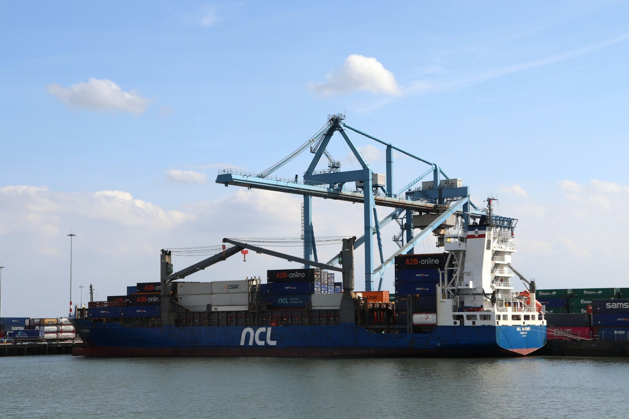 Containerschip aangemeerd aan de kade naast een containerkraan in een zeehaven